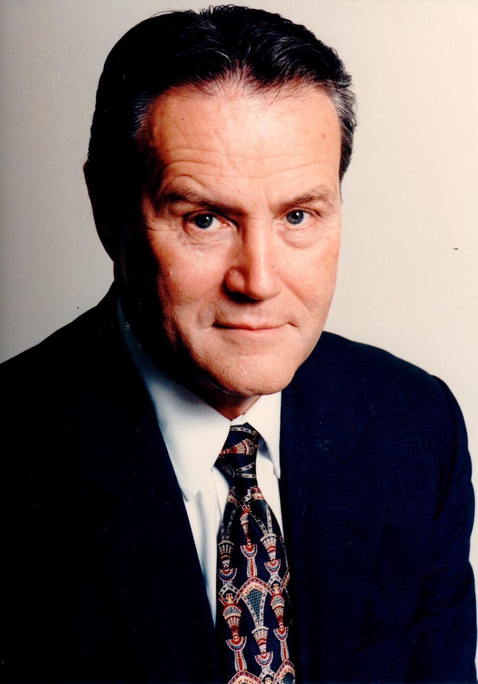 A man in a suit and tie looks at the camera