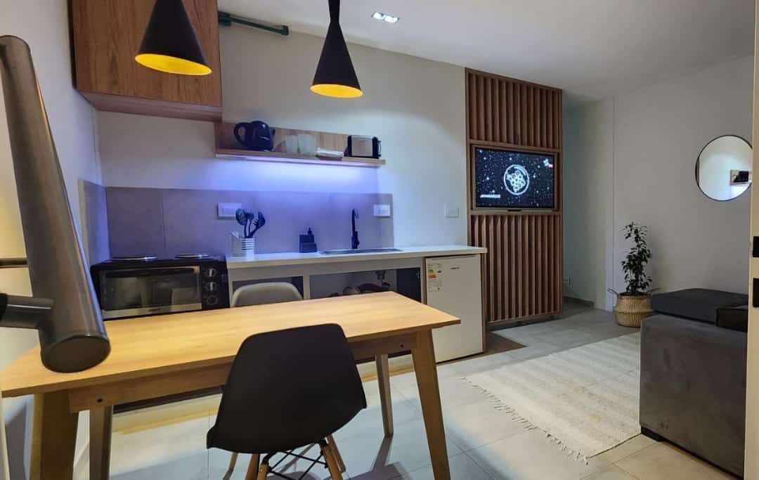 Acogedor estudio con cocina, comedor y TV. Detalles en madera, decoración minimalista e iluminación cálida.