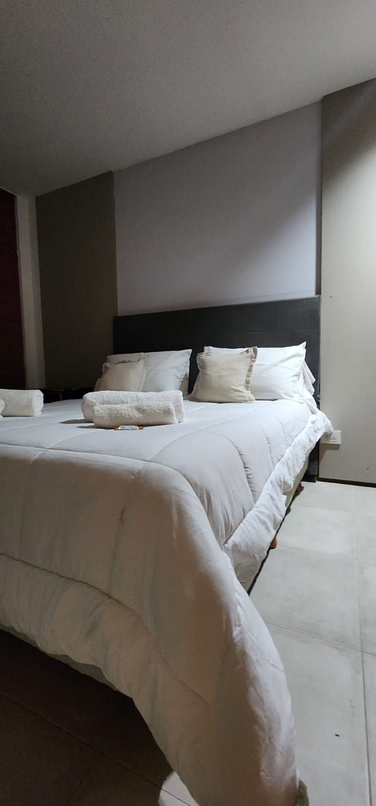 Una cama con ropa de cama y almohadas blancas, con toallas sobre la cama.