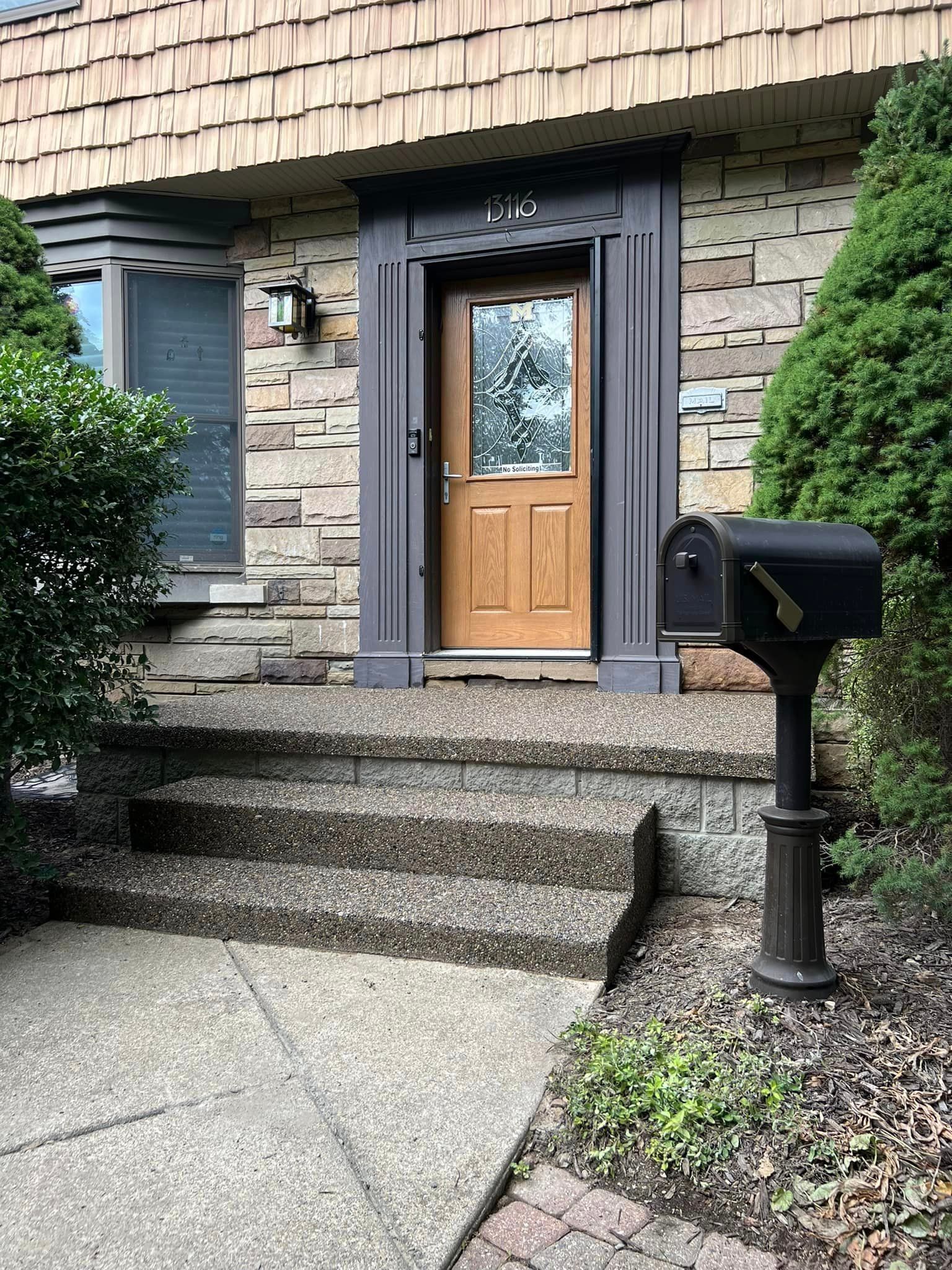 Stone facade house entrance with steps, door, mailbox.