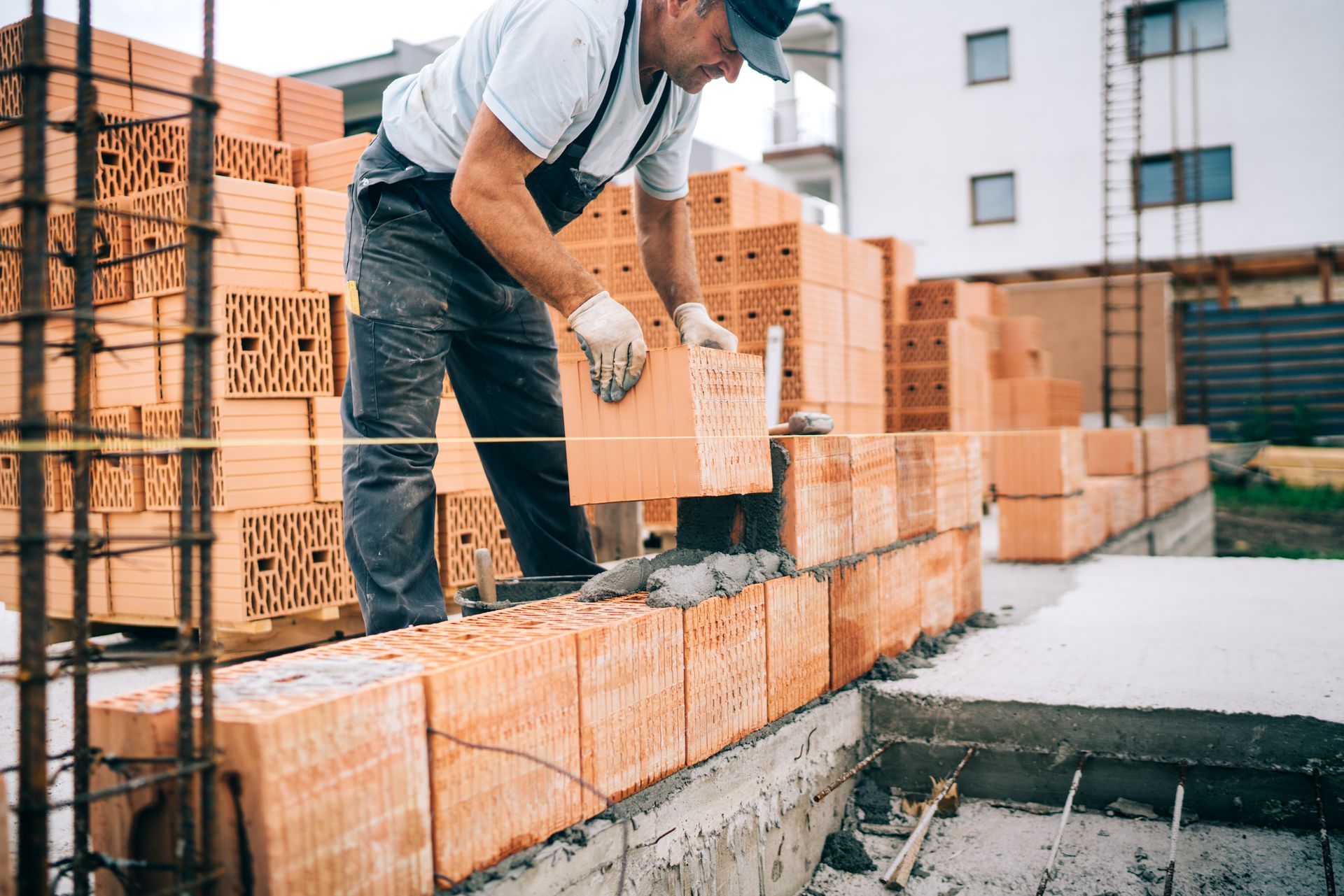 Construction worker laying bricks on a building wall at a worksite
