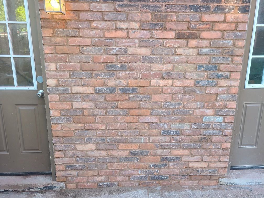 Brick wall between two brown doors, with a light fixture above.