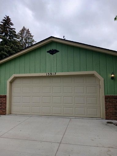 Green house with beige garage door; address 