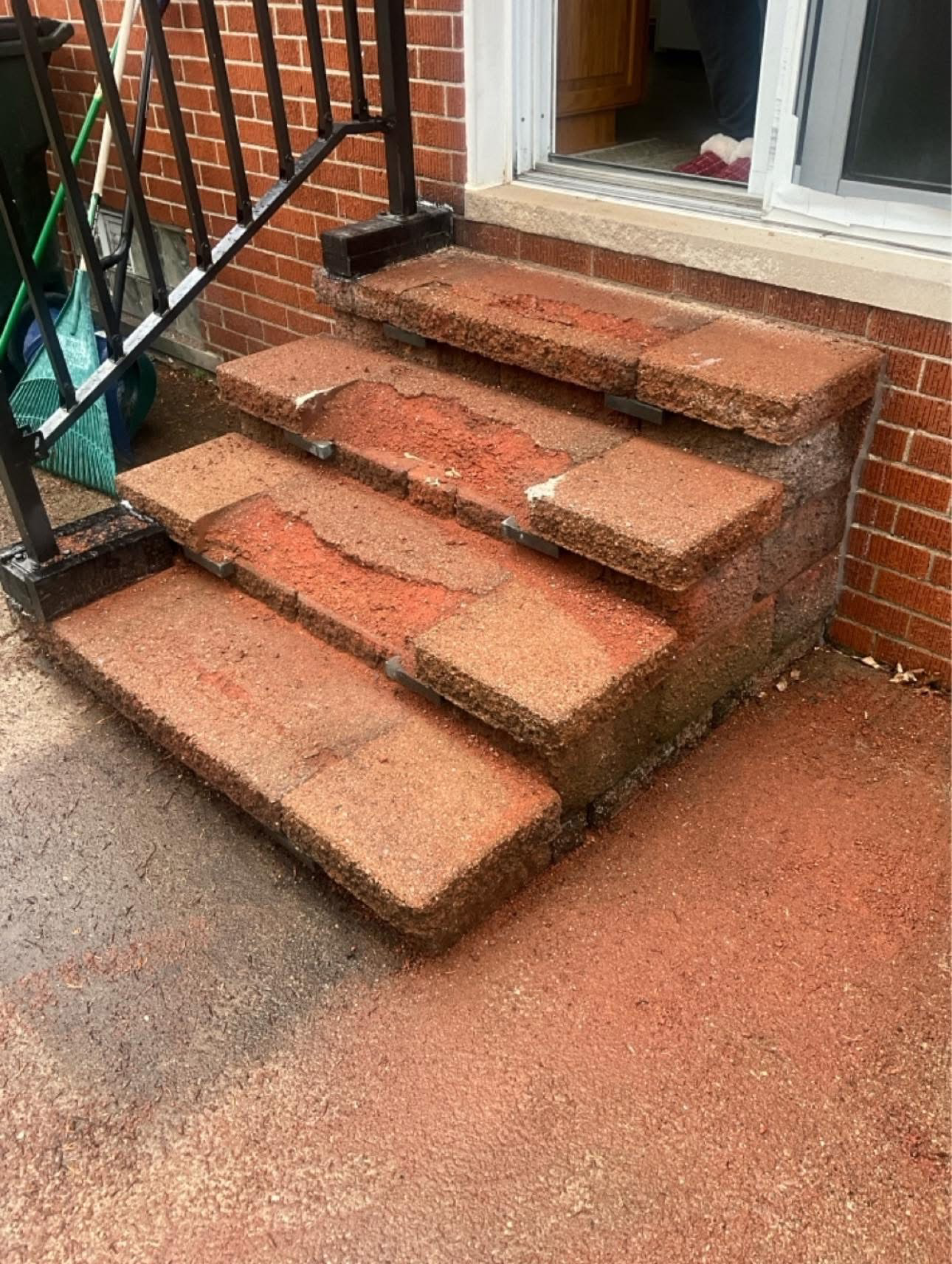 Brick front steps with black metal railing beside a house entrance