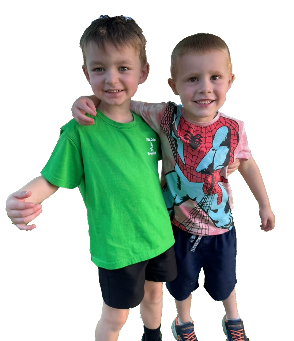Two smiling children standing together, one in a green shirt and the other in a colorful shirt, against a white background