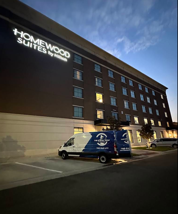 Homewood Suites hotel at dusk with a blue delivery van parked outside