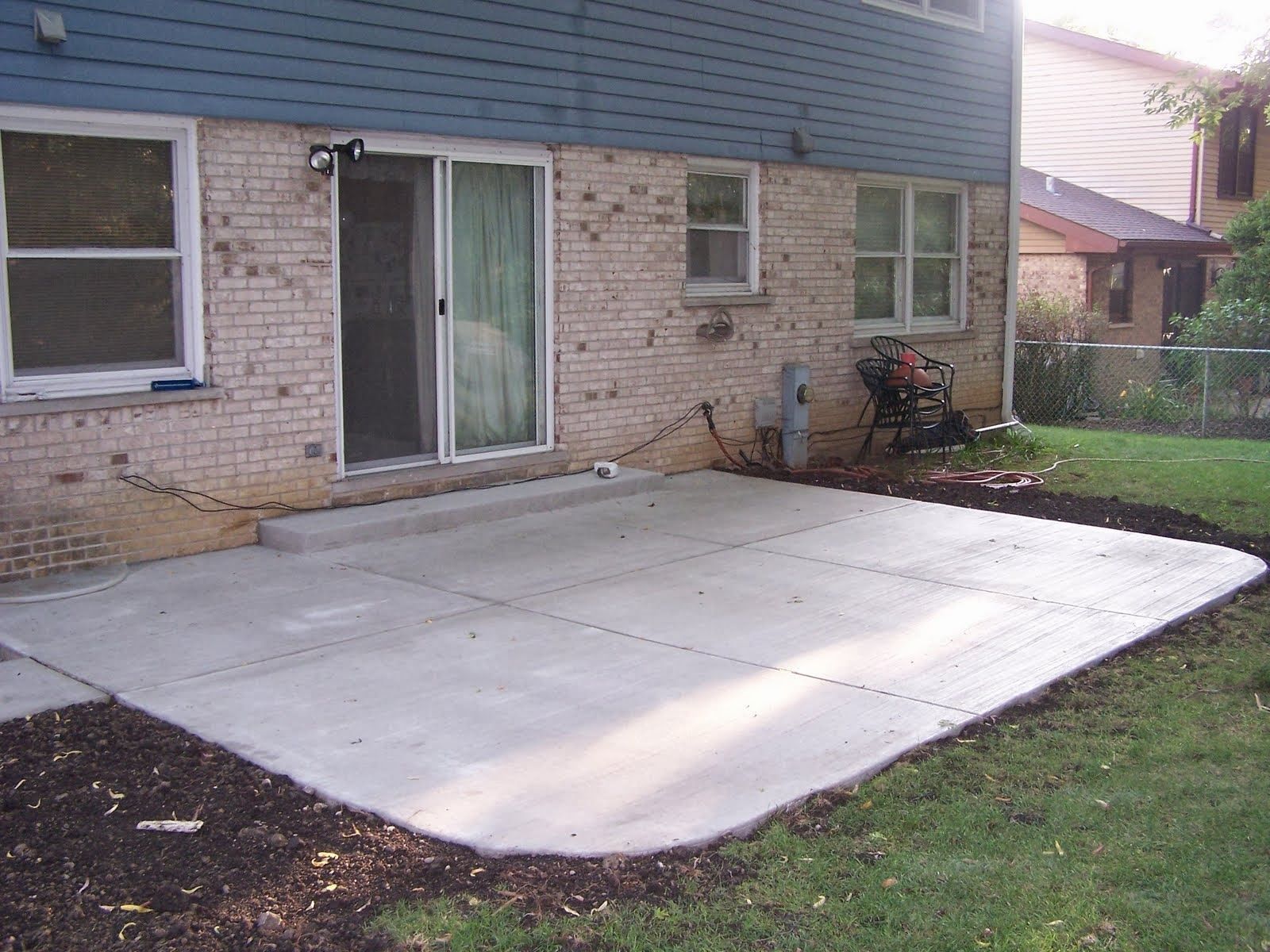 Concrete patio next to a house with a sliding glass door and windows. Mulch borders the patio in Schaumburg IL. 