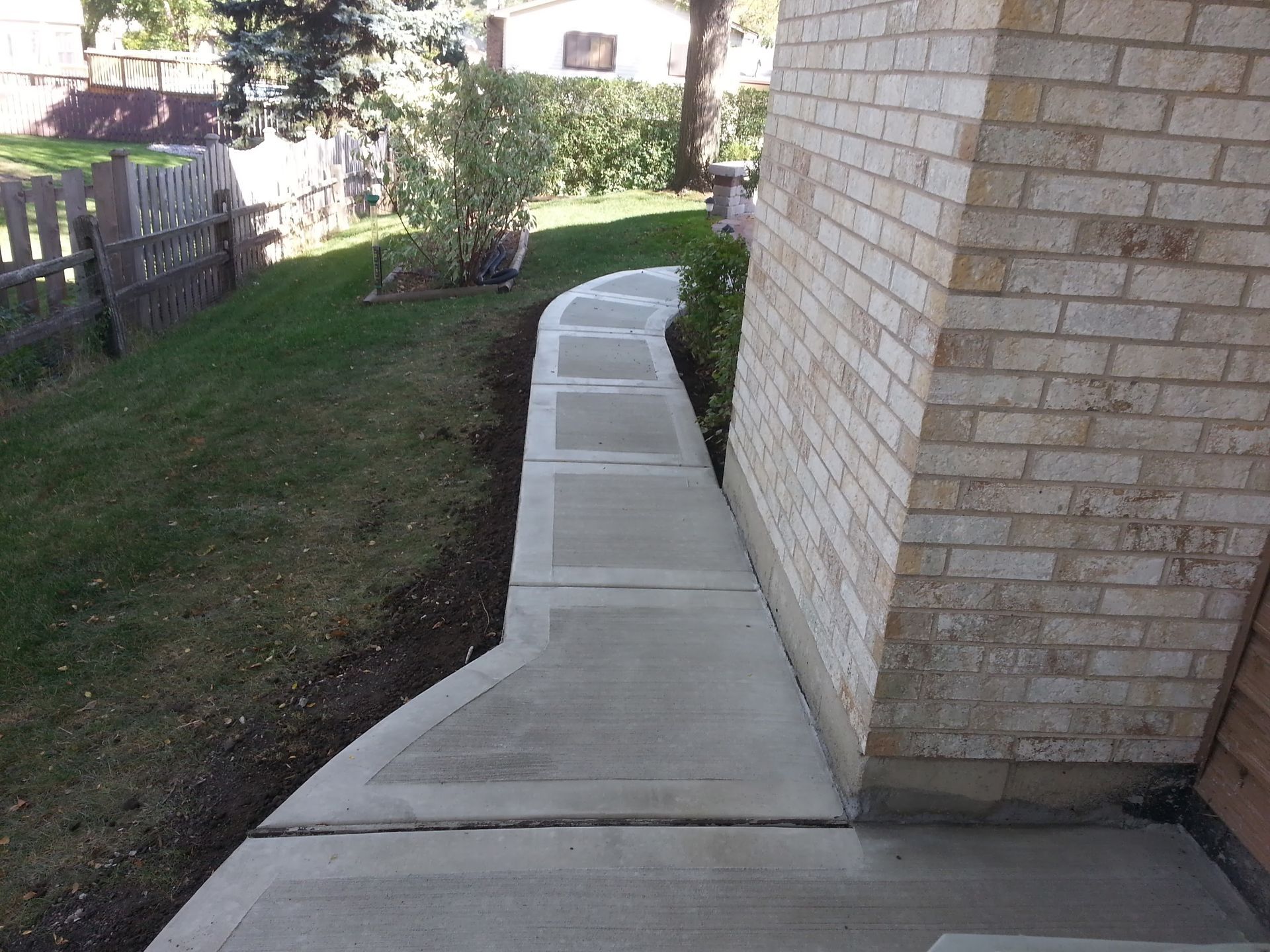 Concrete walkway beside a brick building and grass lawn in Glen Elly IL