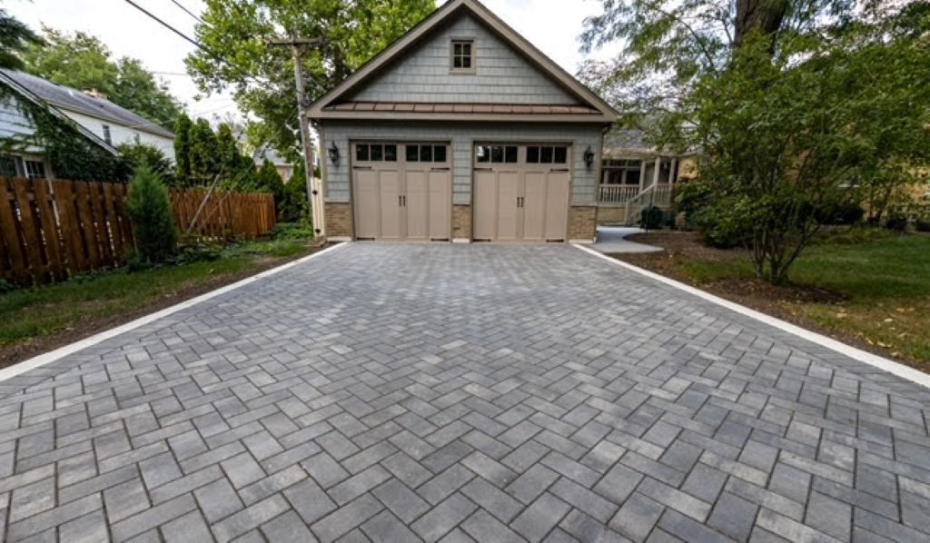 Newly paved concrete driveway leading to a brick house with large windows and a wooden fence in Elmhust IL