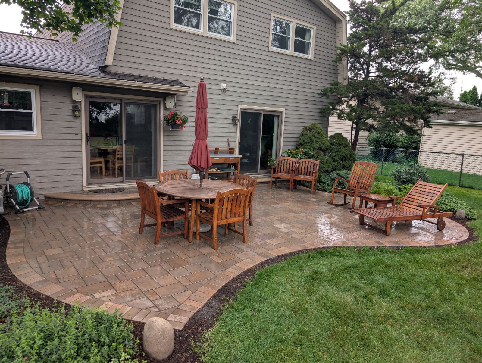Curved earth-tone brick paver patio designed for an Addison backyard.
