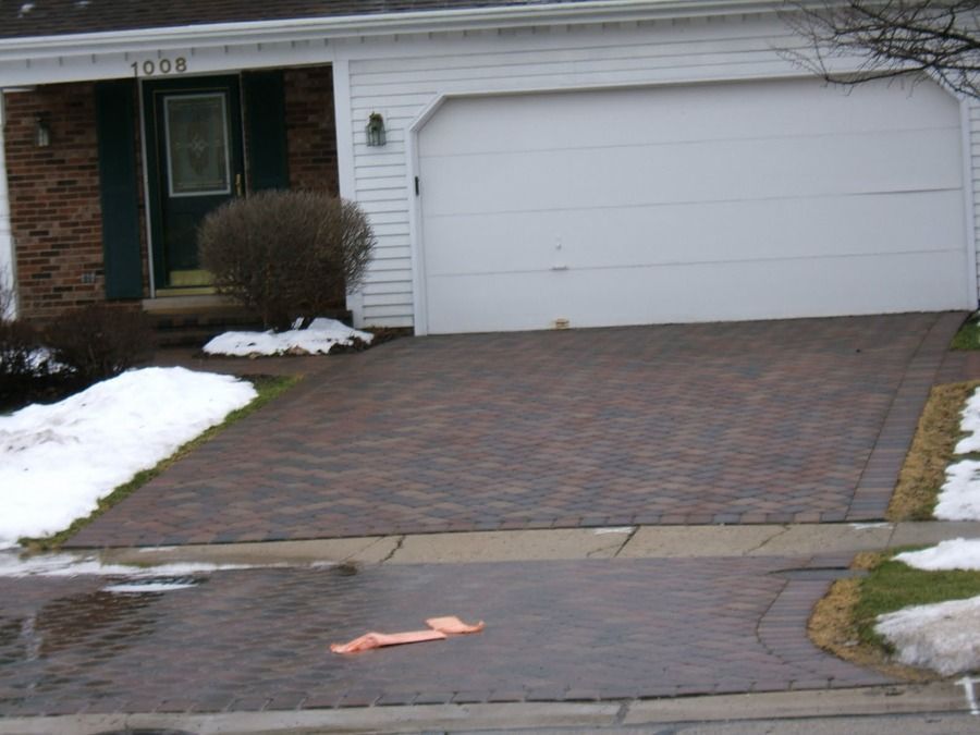 A white house with a brick driveway and a white garage door