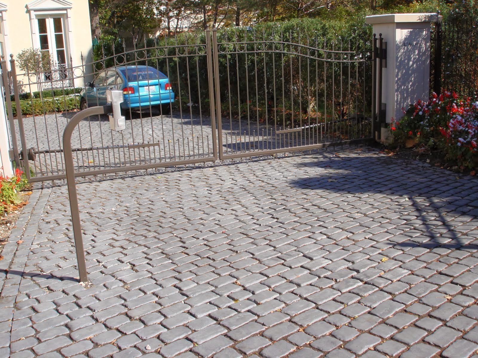 A blue car is parked in a driveway behind a gate