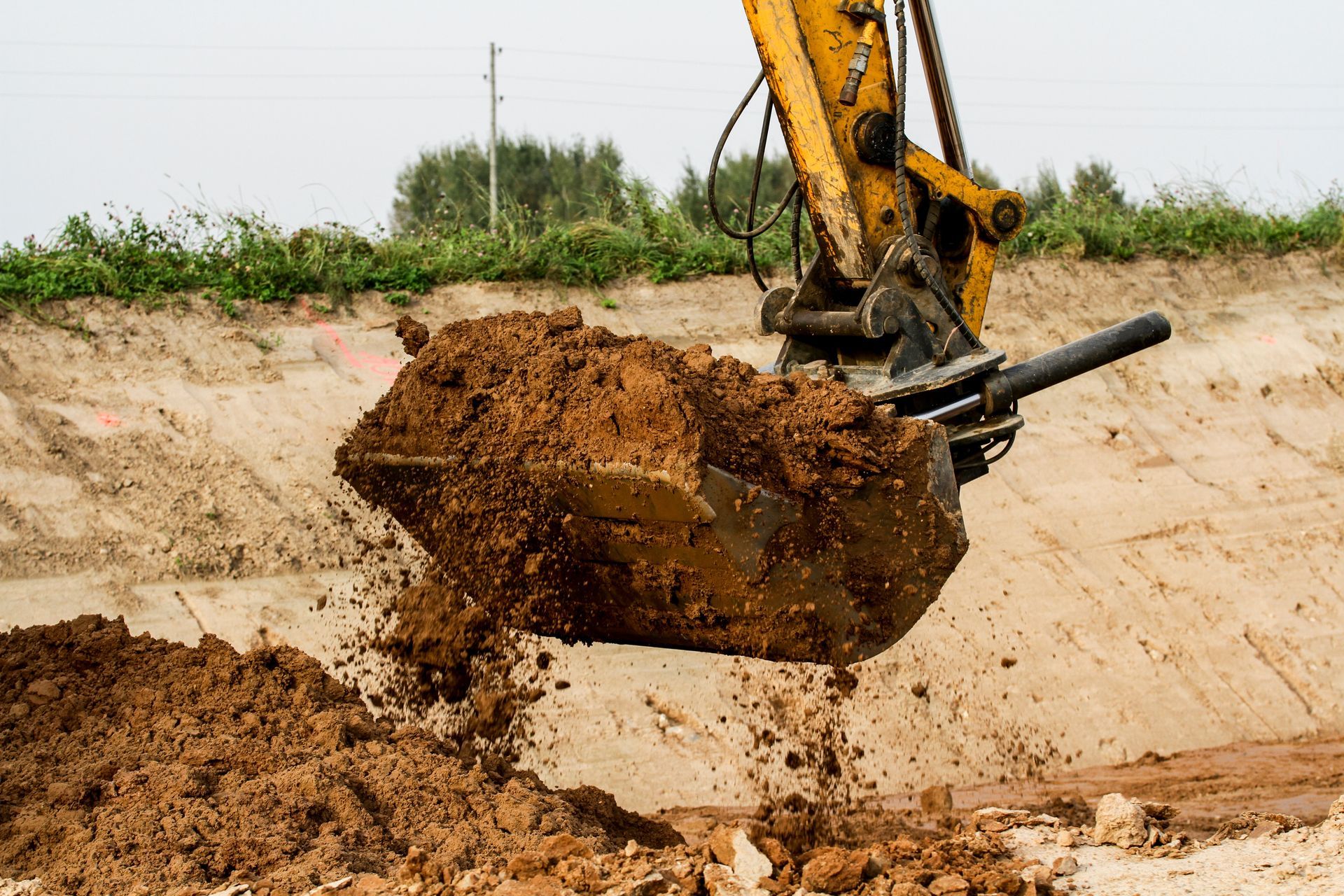 Construction worker in a hard hat reviewing plans on a dirt site with excavators in the background Construction worker in a hard hat reviewing plans on a dirt site with excavators in the background