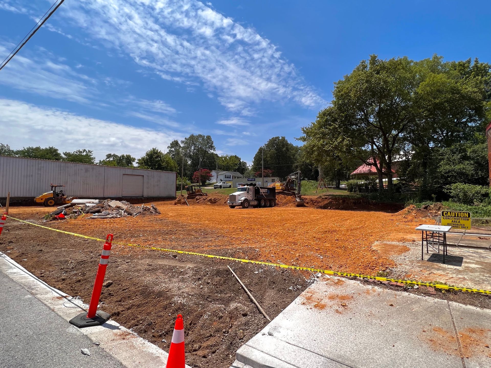 Outdoor dirt lot marked by small red and yellow flags, with trees and fencing in the background