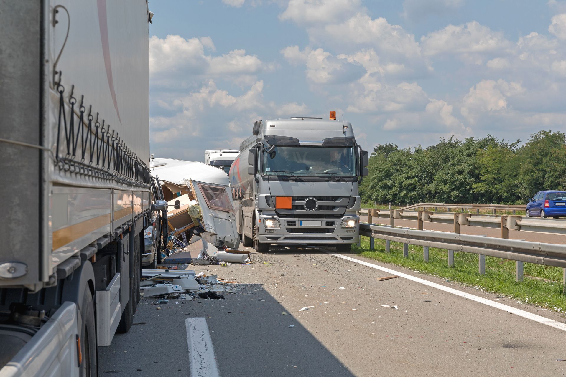 Truck collision on highway with debris scattered between two trucks and a damaged roadside barrier