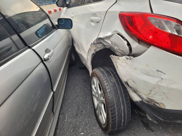 Two cars are parked next to each other and one has a damaged fender.