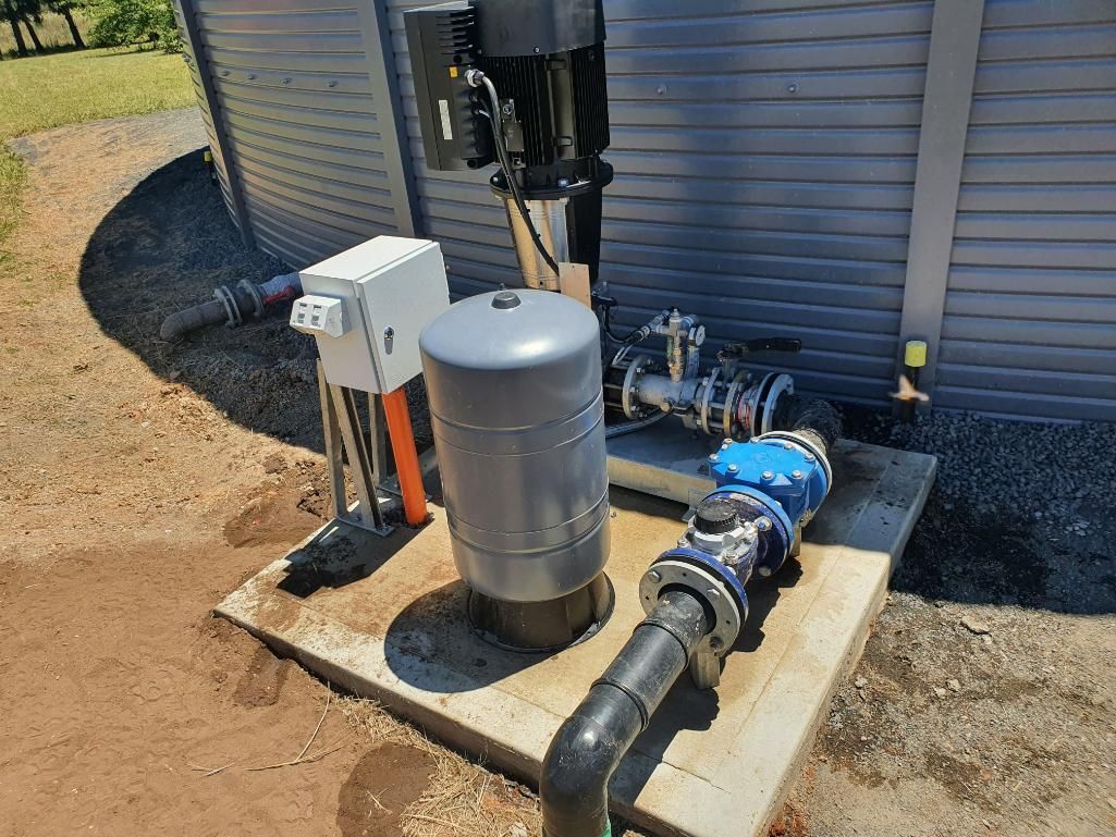 A Water Pump Is Sitting on Top of A Concrete Platform Next to A Building — Peel Irrigation & Water Supplies in Taminda, NSW