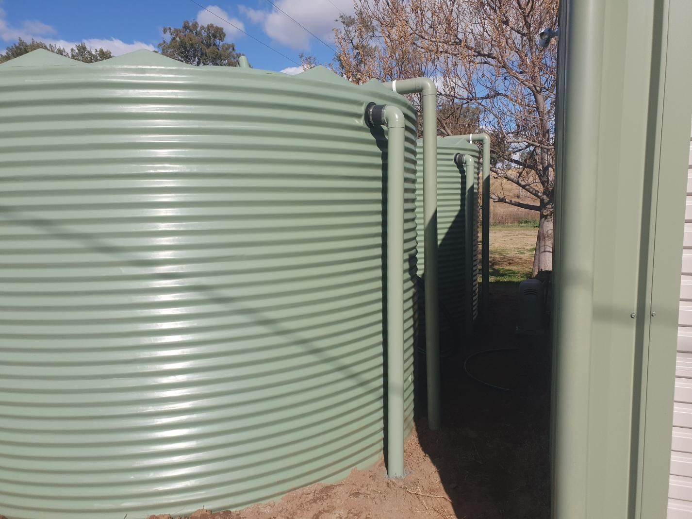 A Row of Green Water Tanks Sitting Next to Each Other — Peel Irrigation & Water Supplies in Taminda, NSW