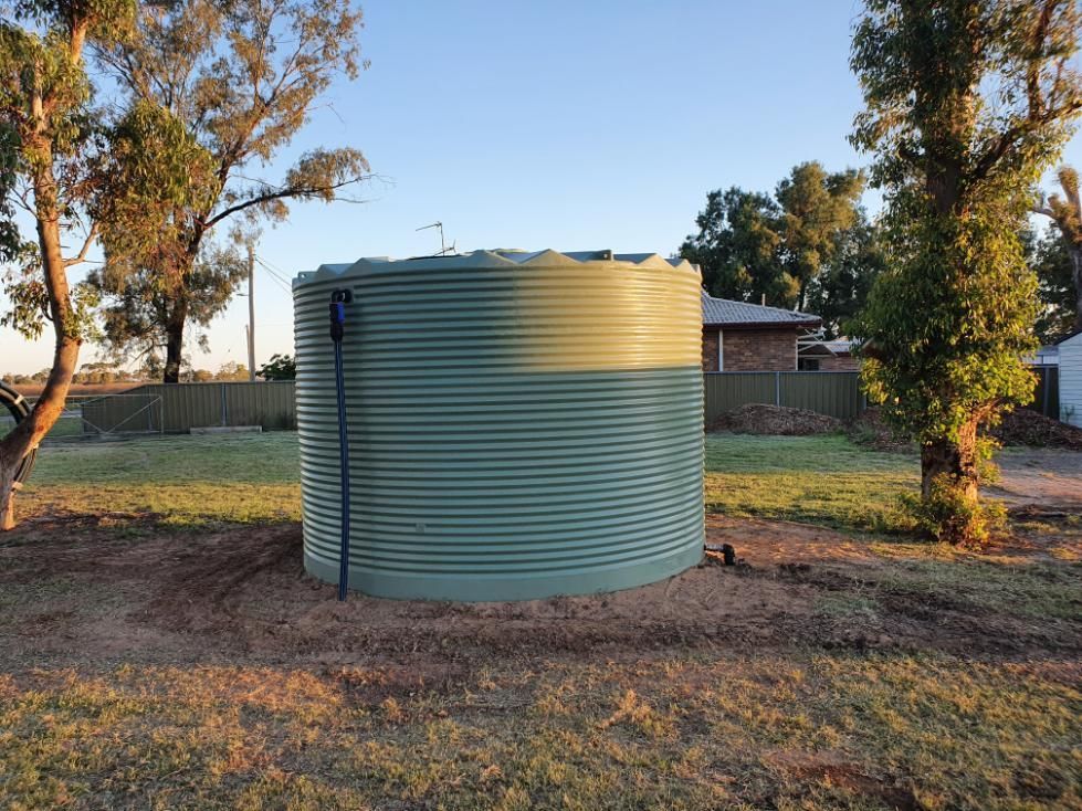A Large Green Water Tank Is Sitting in The Middle of A Grassy Field — Peel Irrigation & Water Supplies in Taminda, NSW