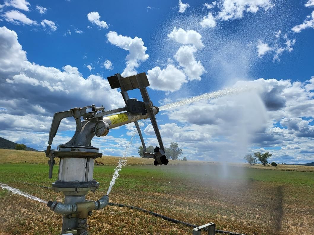 A Sprinkler Is Spraying Water in A Field on A Cloudy Day — Peel Irrigation & Water Supplies in Taminda, NSW