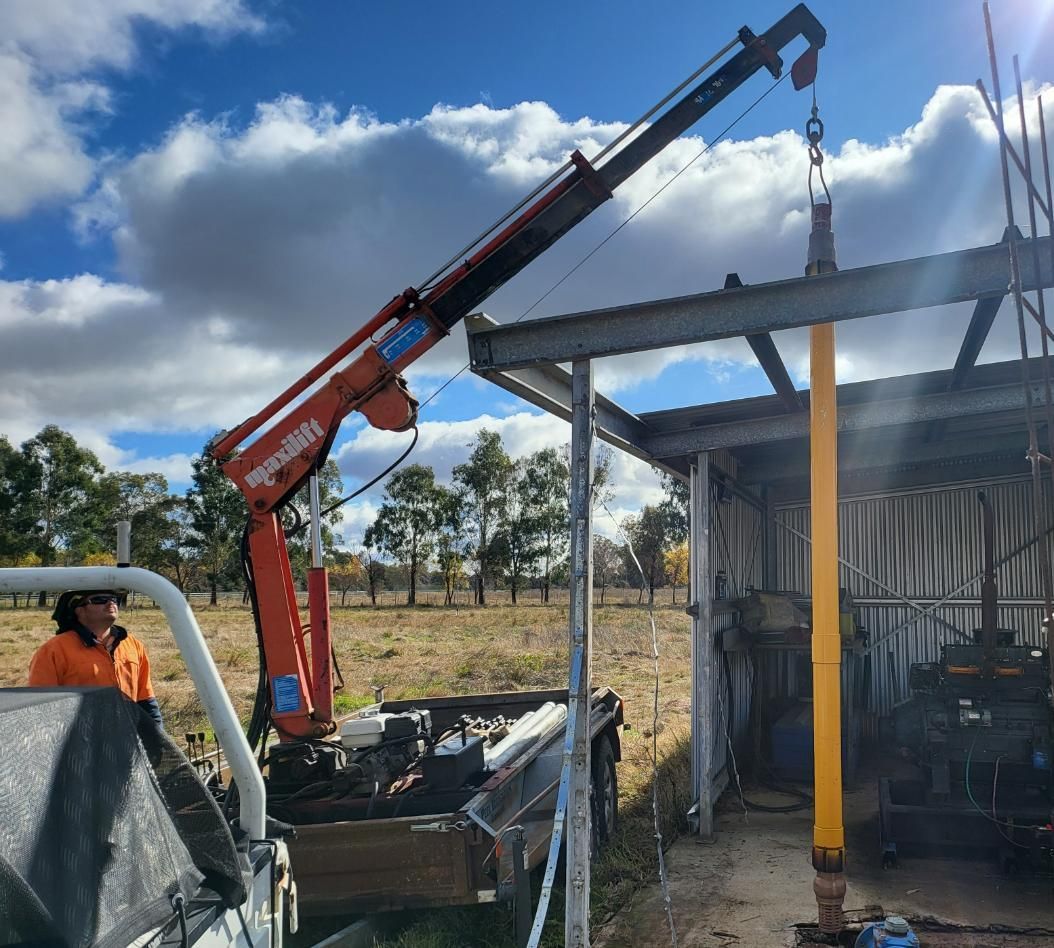 A Man Is Standing Next to A Truck with A Crane Attached to It — Peel Irrigation & Water Supplies in Taminda, NSW