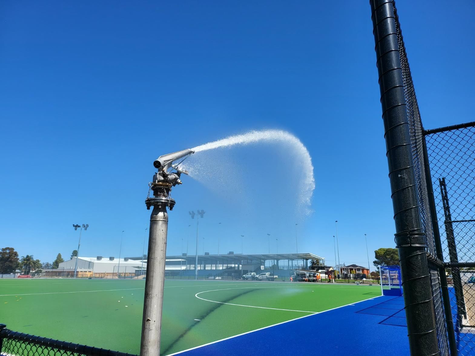 A Hose Is Spraying Water on A Tennis Court — Peel Irrigation & Water Supplies in Taminda, NSW
