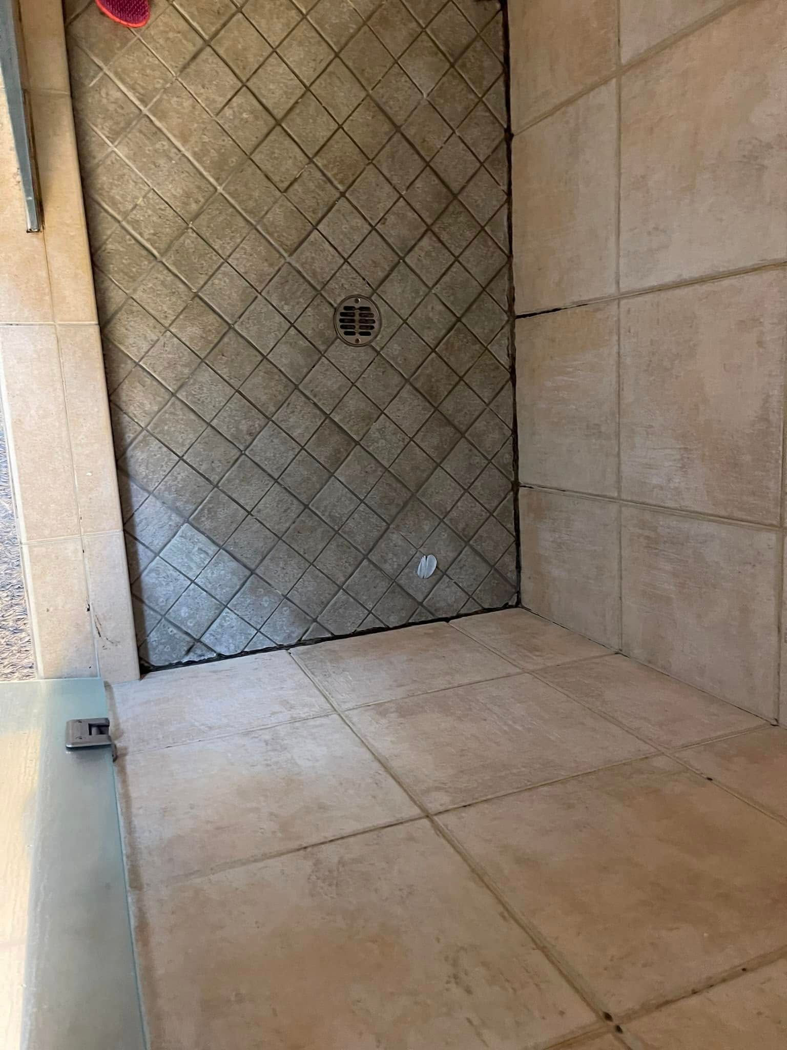 Shower with tiled walls and floor, diagonal pattern on back wall.
