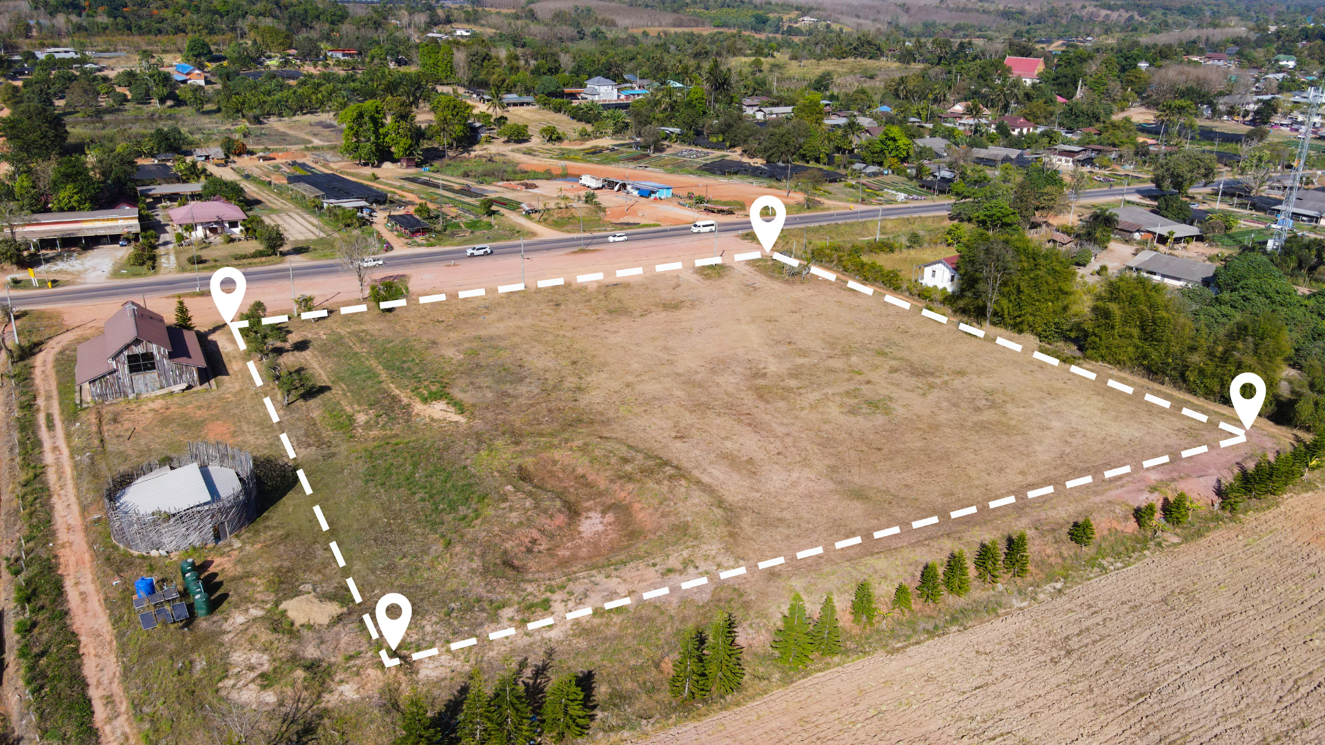 An aerial view of a field with a white line drawn around it.