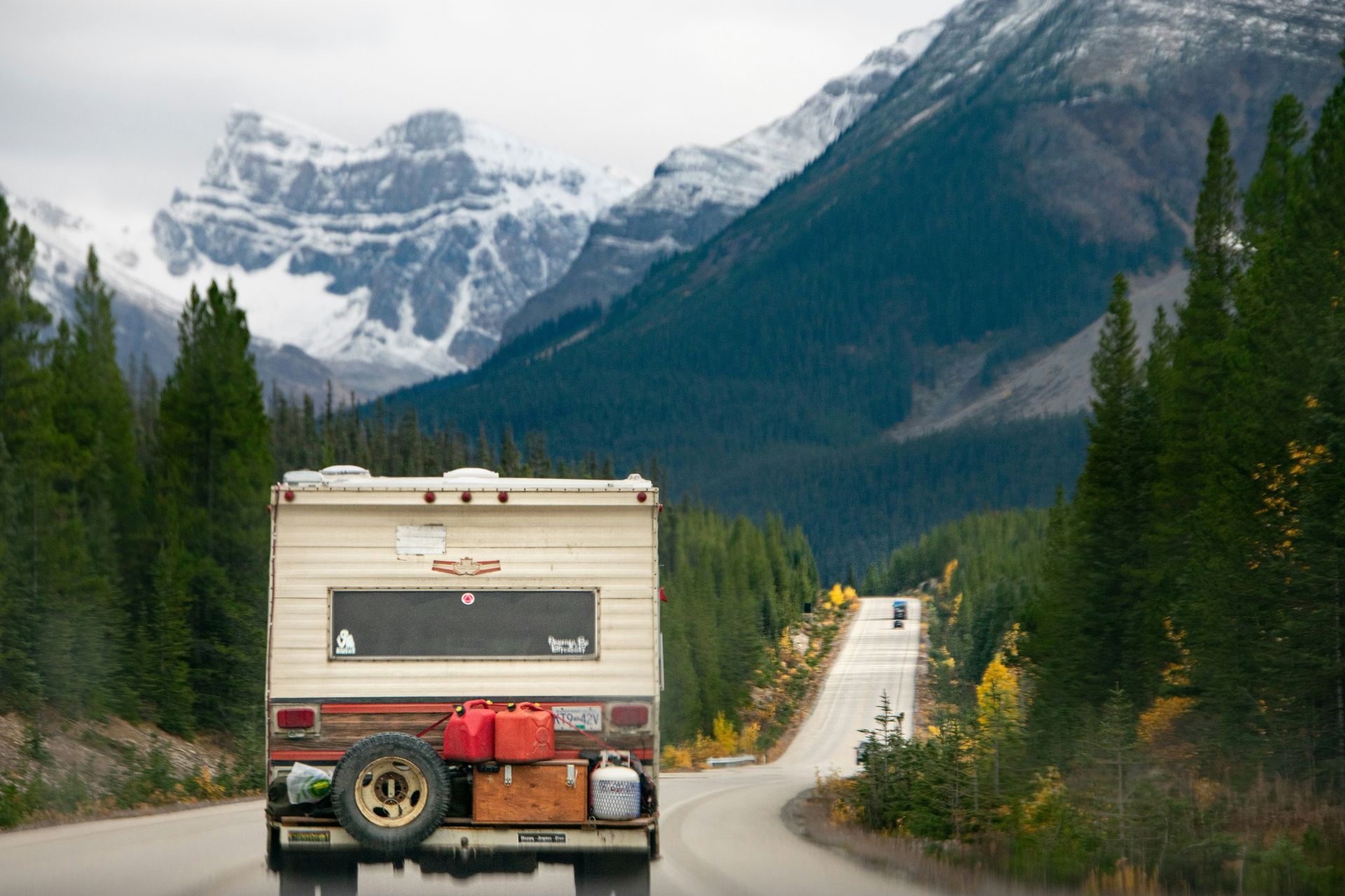 RV driving along a mountain road surrounded by pine trees