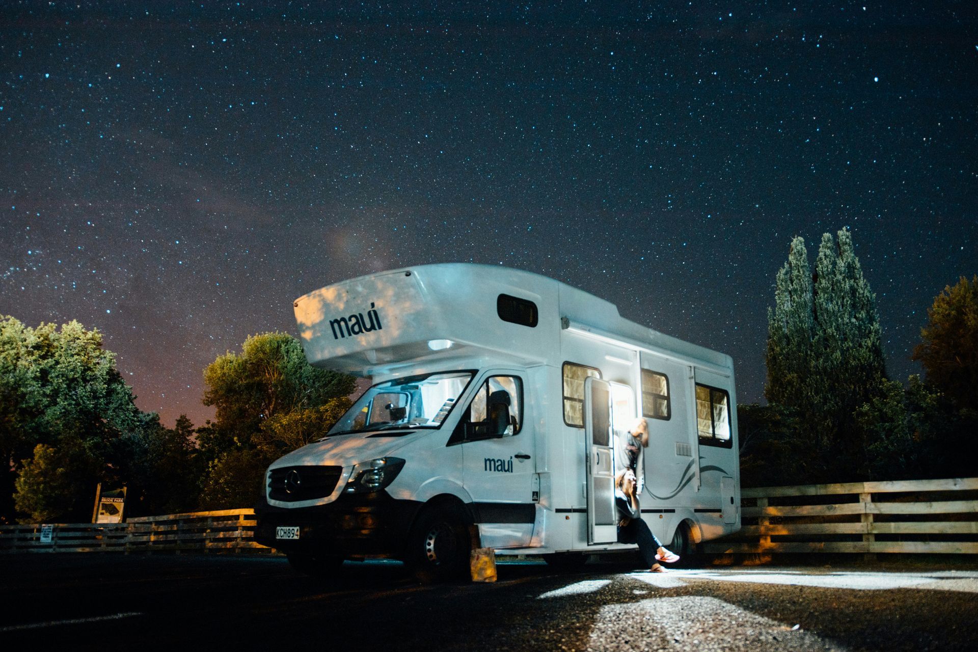 Recreational vehicle parked at night under a starry sky with interior lights on during off-season st