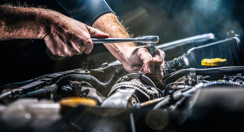 auto mechanic working on car engine in garage