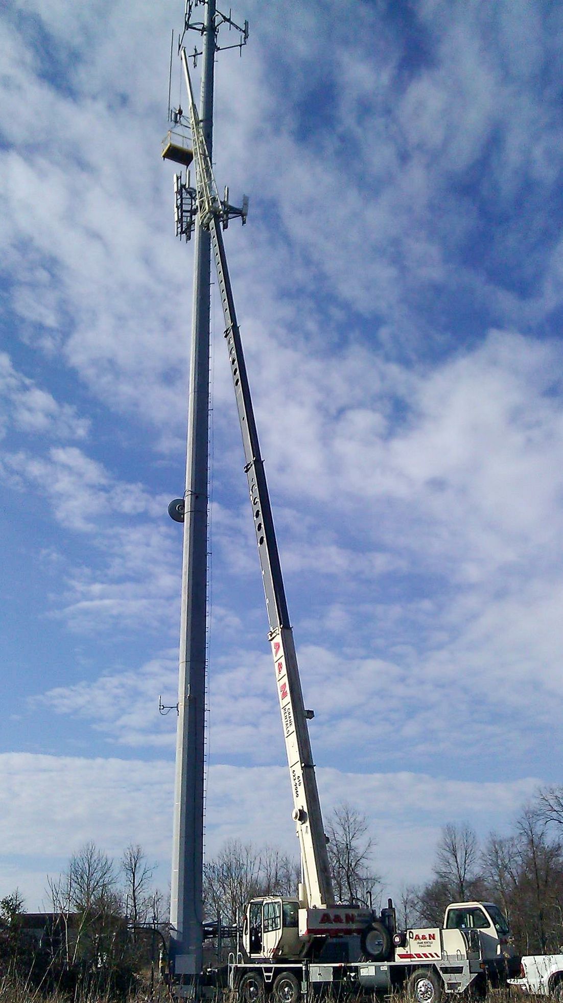 A crane from A&N Crane Rental reaching up to the top of a tall pole.