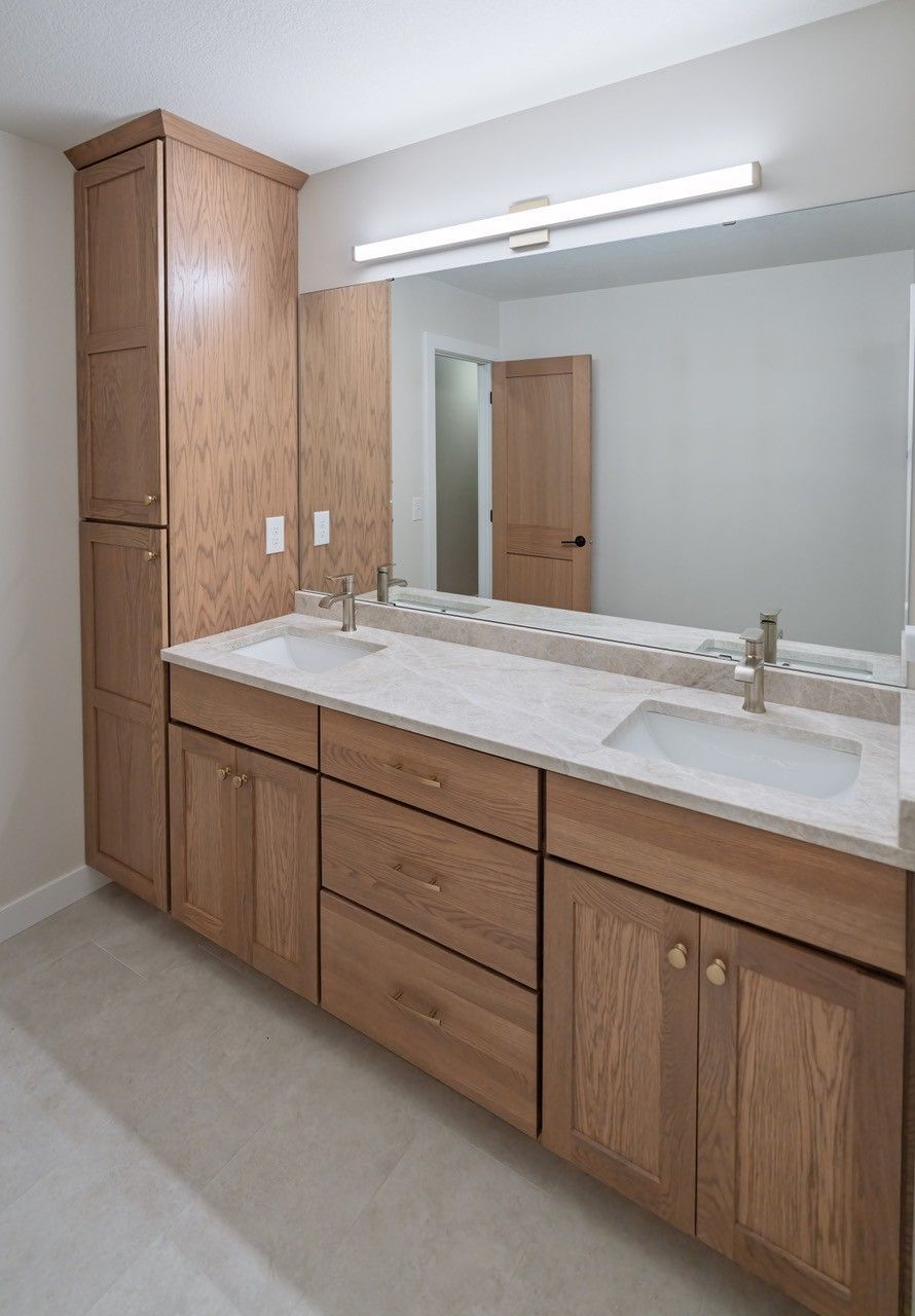 Bathroom vanity with wooden cabinets, double sinks, and a large mirror.