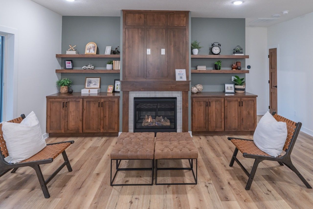 Living room with fireplace, built-in cabinetry, floating shelves, two chairs, and a coffee table.