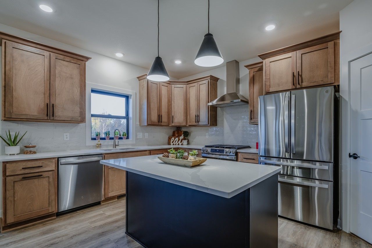 Modern kitchen with wooden cabinets, stainless steel appliances, and a black island.