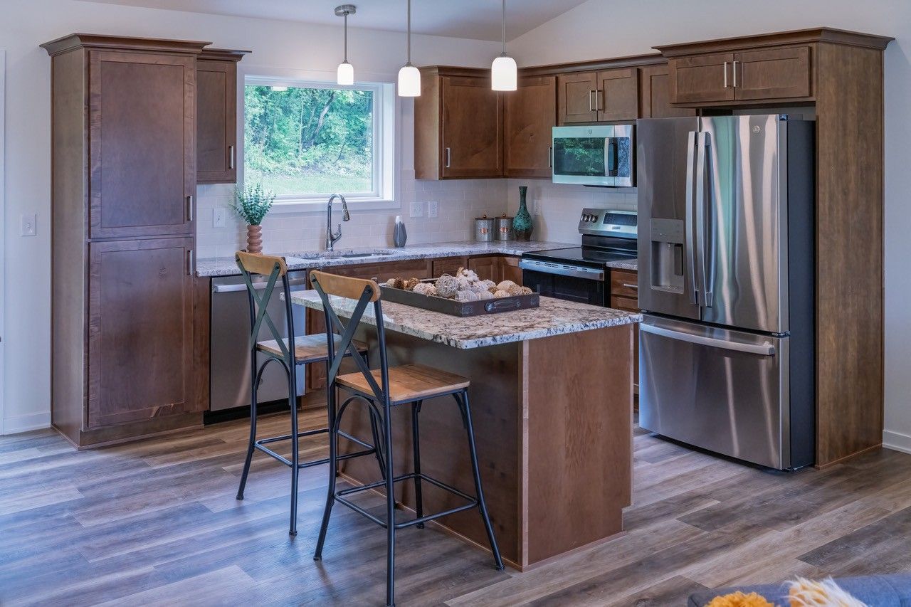 Kitchen with wood cabinets, stainless steel appliances, island, and bar stools.