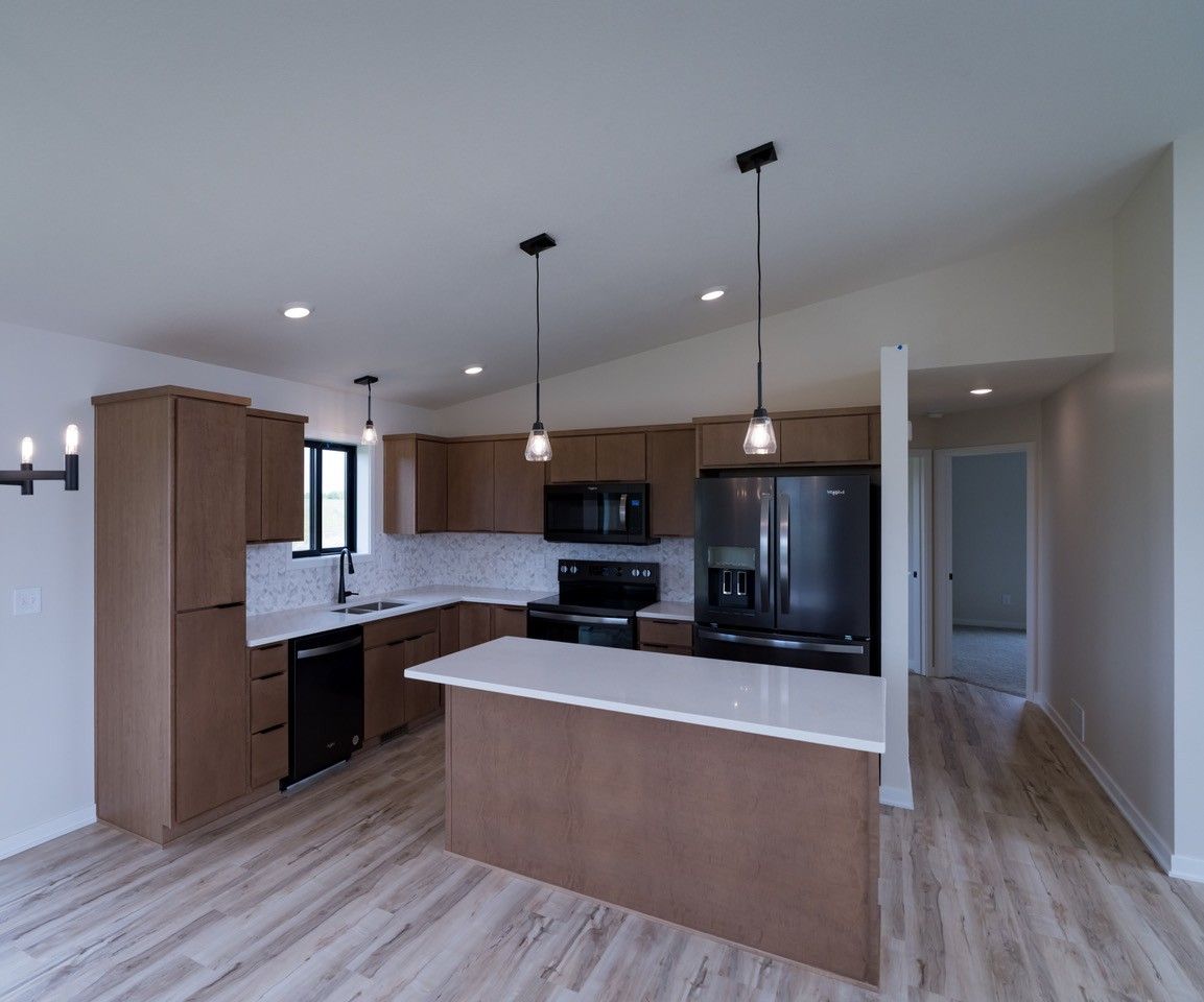 Modern kitchen with brown cabinets, white countertops, and black appliances.