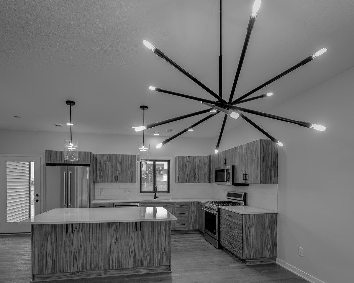 Black and white kitchen with wood cabinets, island, and large sputnik chandelier.