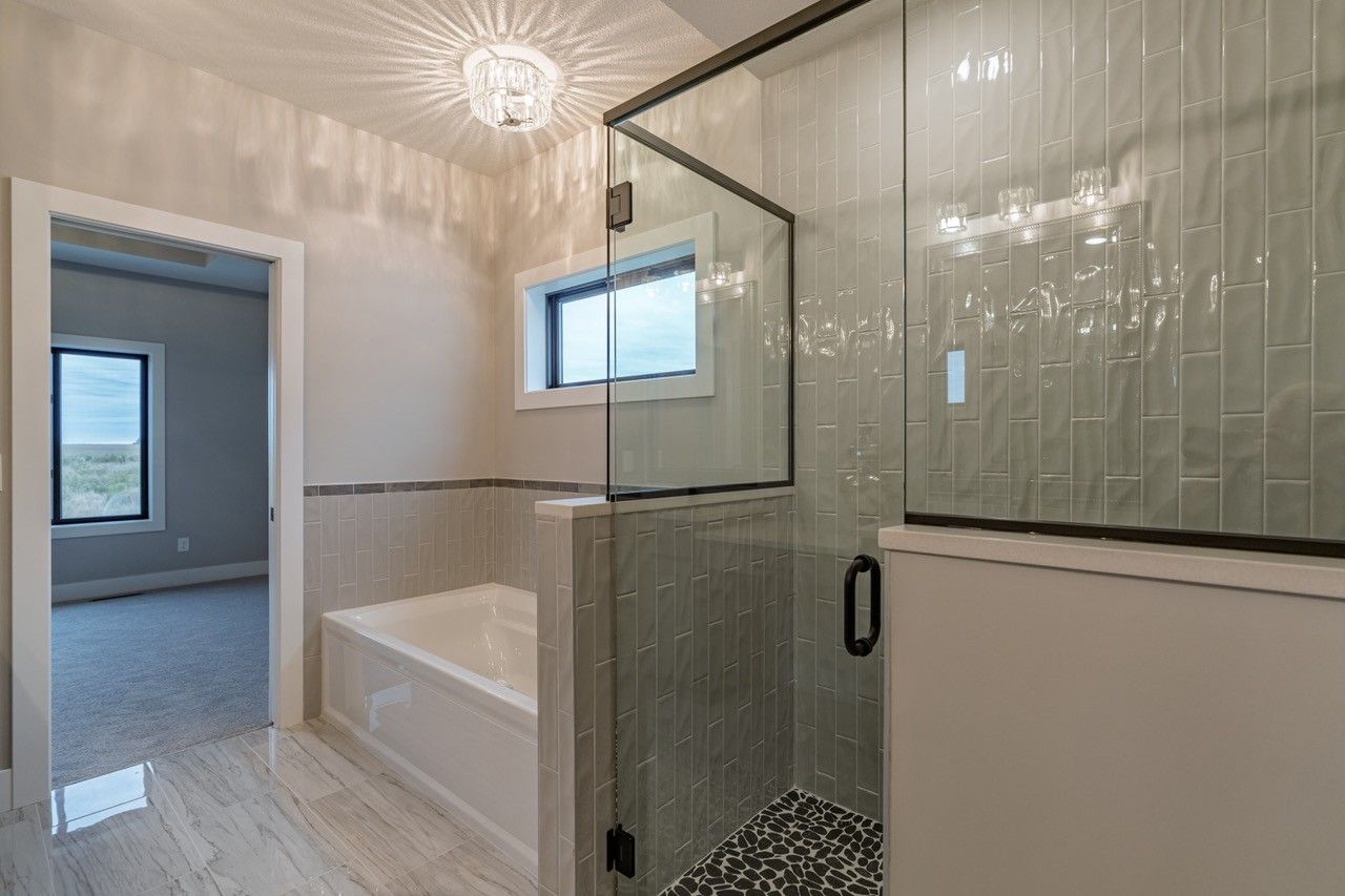 Modern bathroom with glass shower, soaking tub, and white tile walls