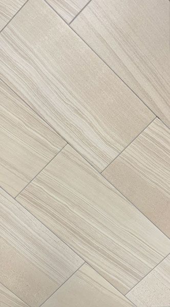 A close up of a white tile floor that looks like wood.
