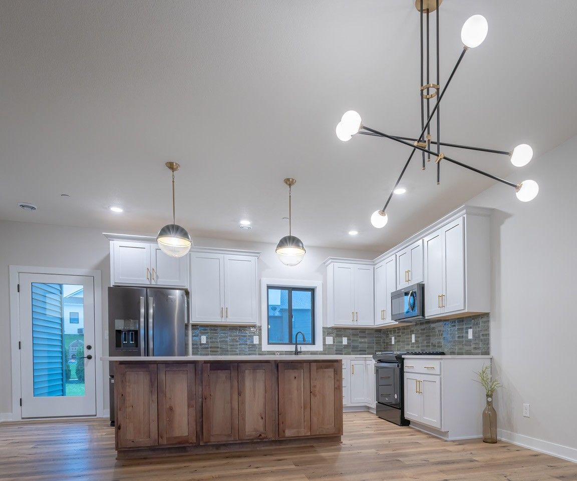 Modern kitchen with white cabinets, wood island, and sputnik chandelier.