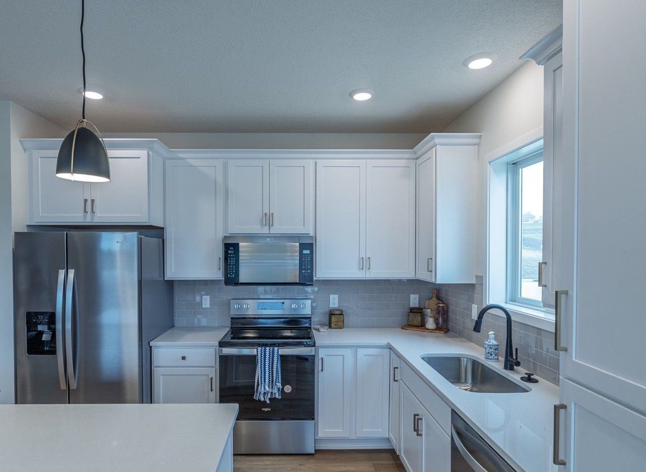 White kitchen with stainless steel appliances, white cabinets, and a sink.