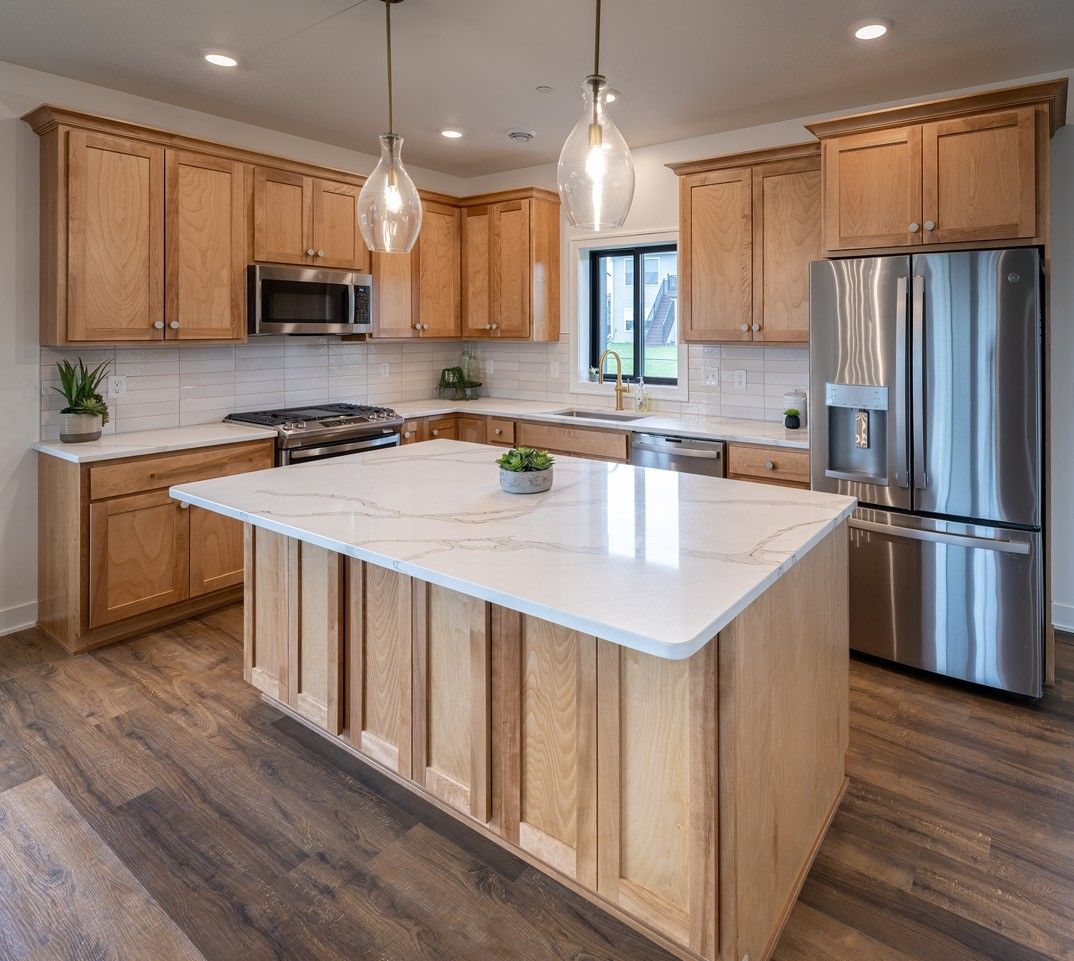 Kitchen with light wood cabinets, white countertops, and stainless steel appliances.