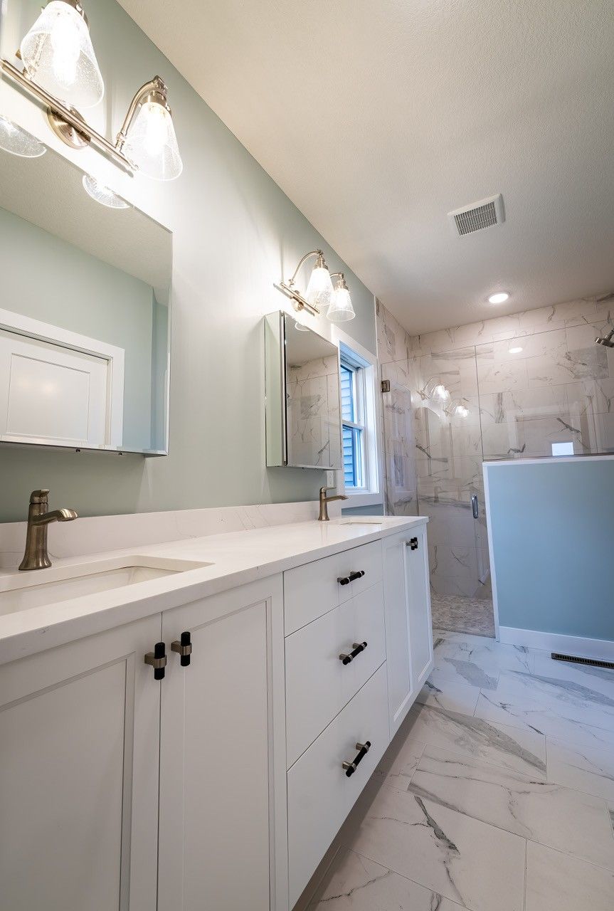 Bathroom with white vanity, marble floors, and light blue walls.