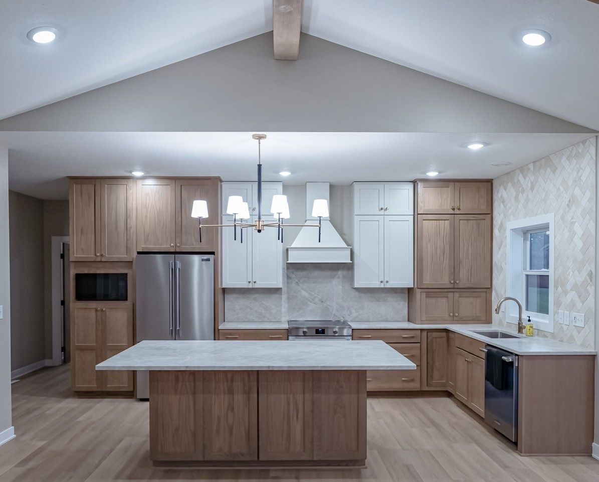 Modern kitchen with light wood cabinets, stainless steel appliances, and white accents.