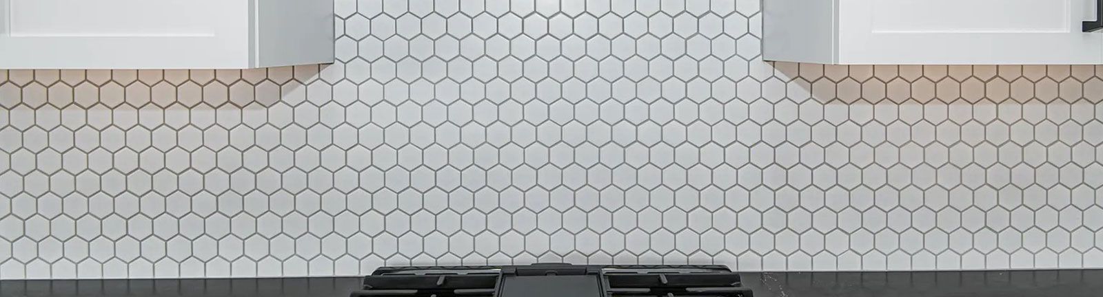 White honeycomb tiles on a backsplash, with dark trim and cabinets visible.