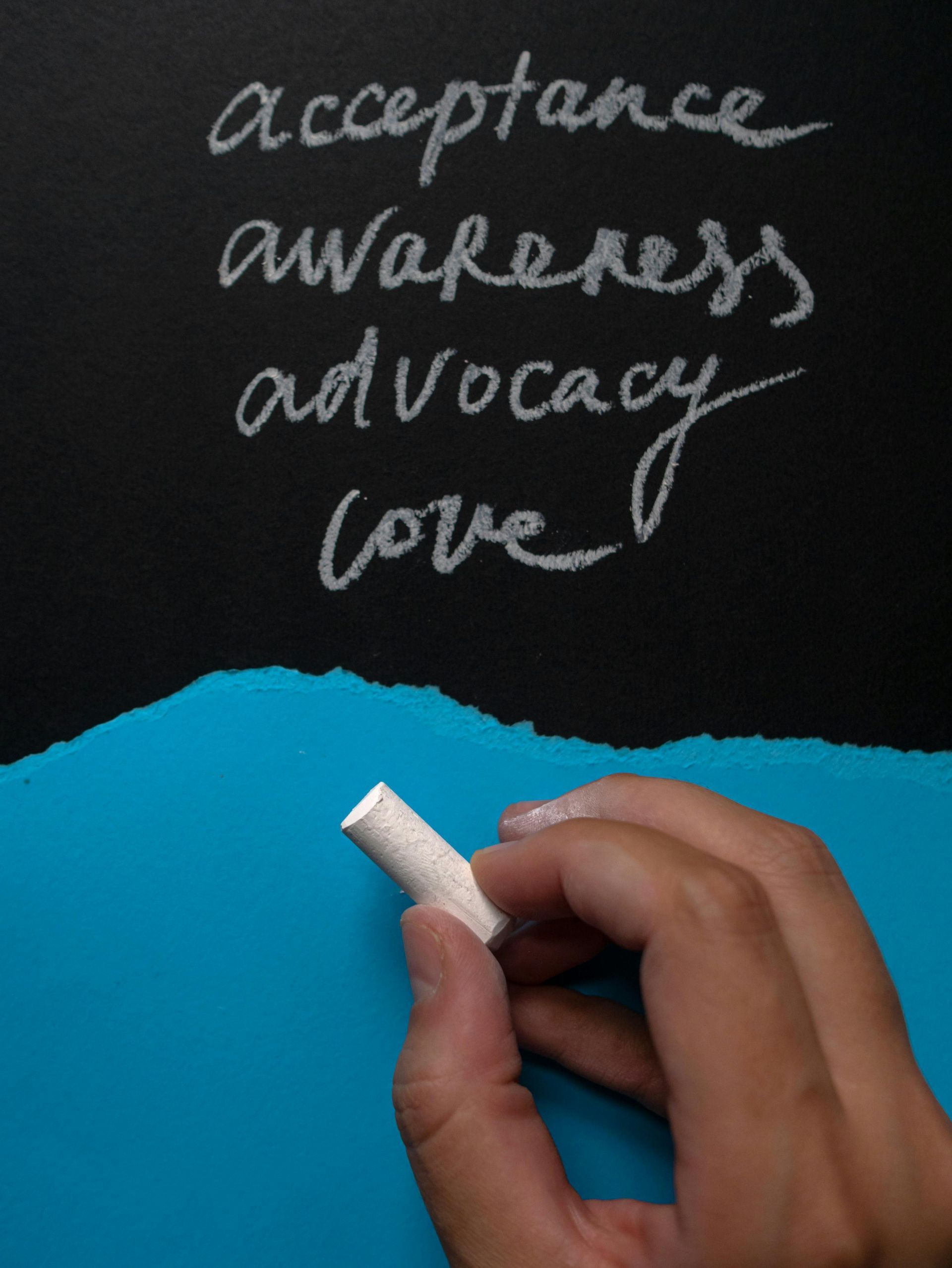 A chalkboard with a hand over the color blue, with writing titled "acceptance awareness advocacy love."