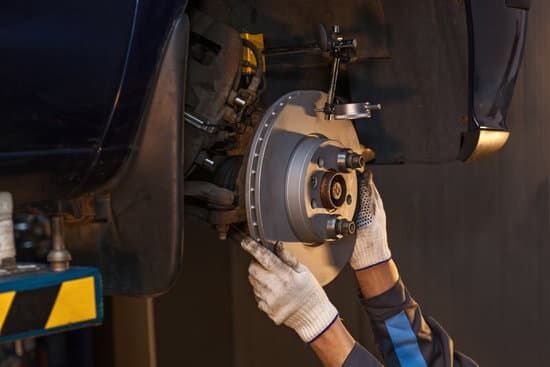 A man is fixing a brake disc on a car in a garage.