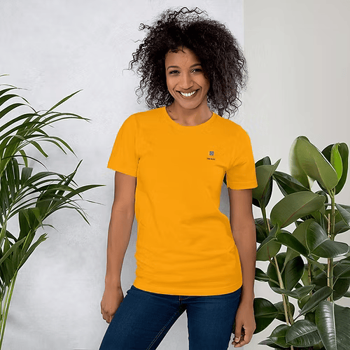 A woman wearing a green t-shirt is standing next to a plant.