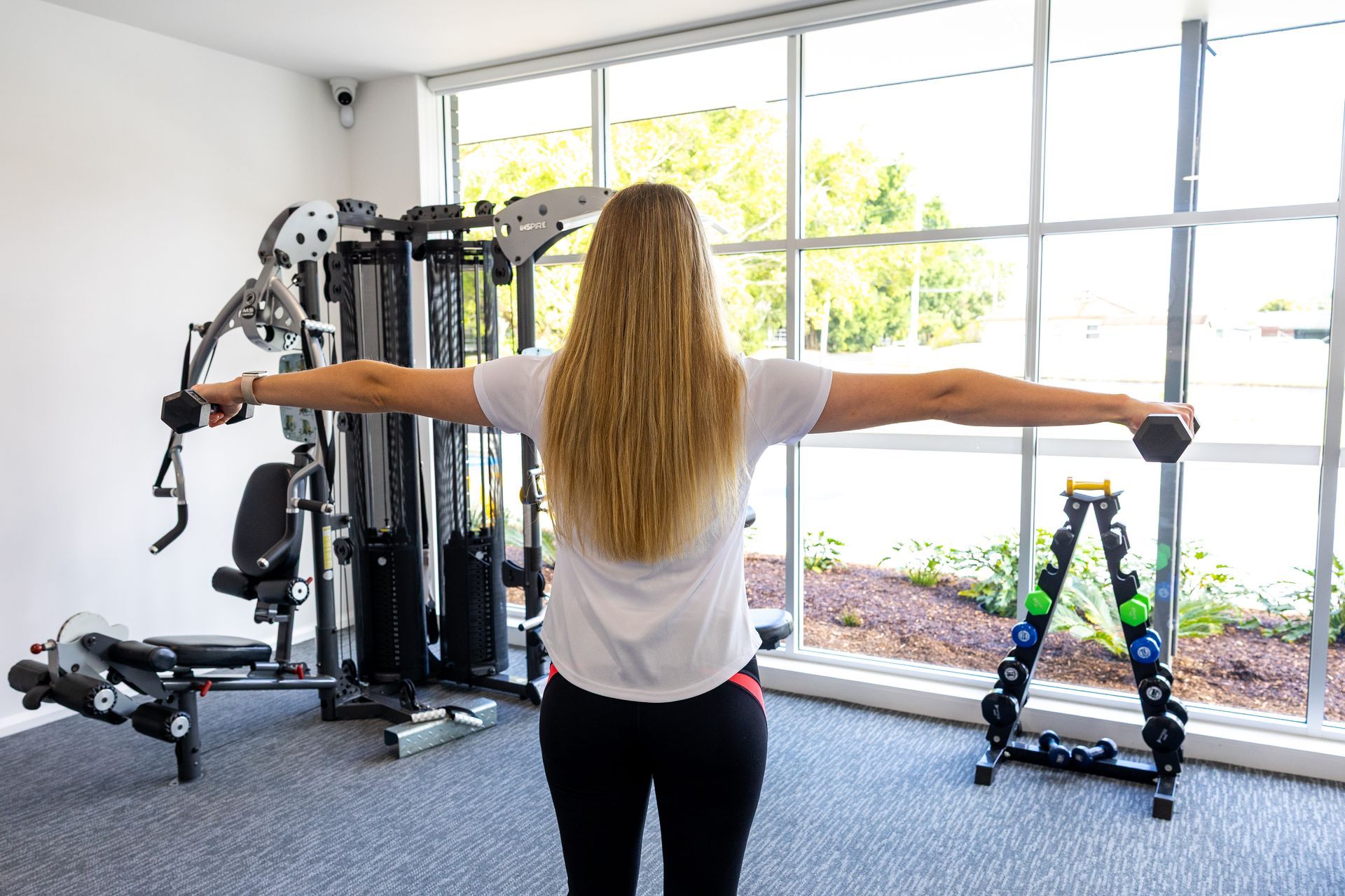Person exercising on a balance platform, arms outstretched, in a bright gym with large windows. — Forerunner Physio In Taree, NSW